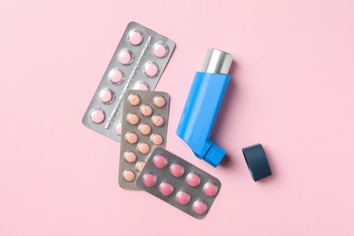 Photo of Asthma inhaler and pills on pink background, flat lay