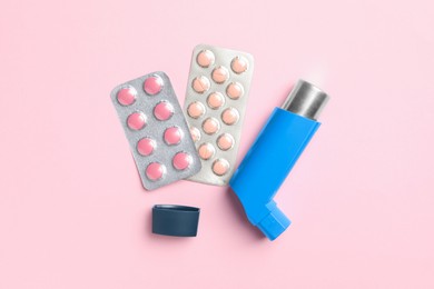 Photo of Asthma inhaler and pills on pink background, flat lay