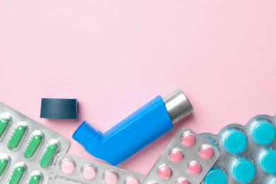 Photo of Asthma inhaler and pills on pink background, flat lay. Space for text