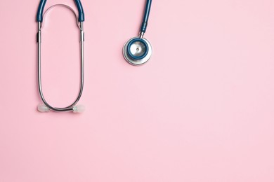 Photo of Stethoscope on pink background, top view. Space for text