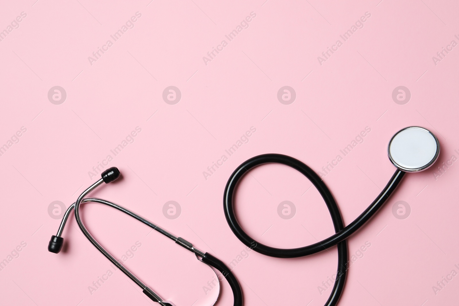 Photo of Stethoscope on pink background, top view. Space for text