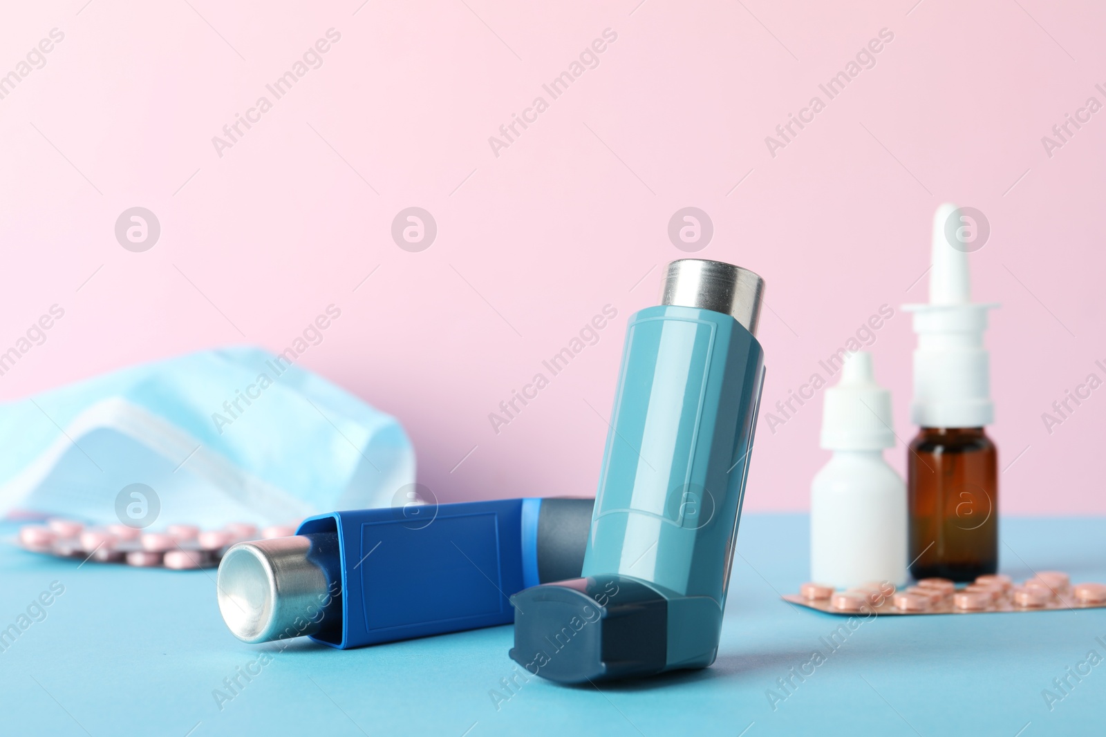 Photo of Asthma inhaler and other medications on color background, closeup