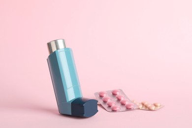 Photo of Inhaler and pills on pink background, closeup. Asthma treatment