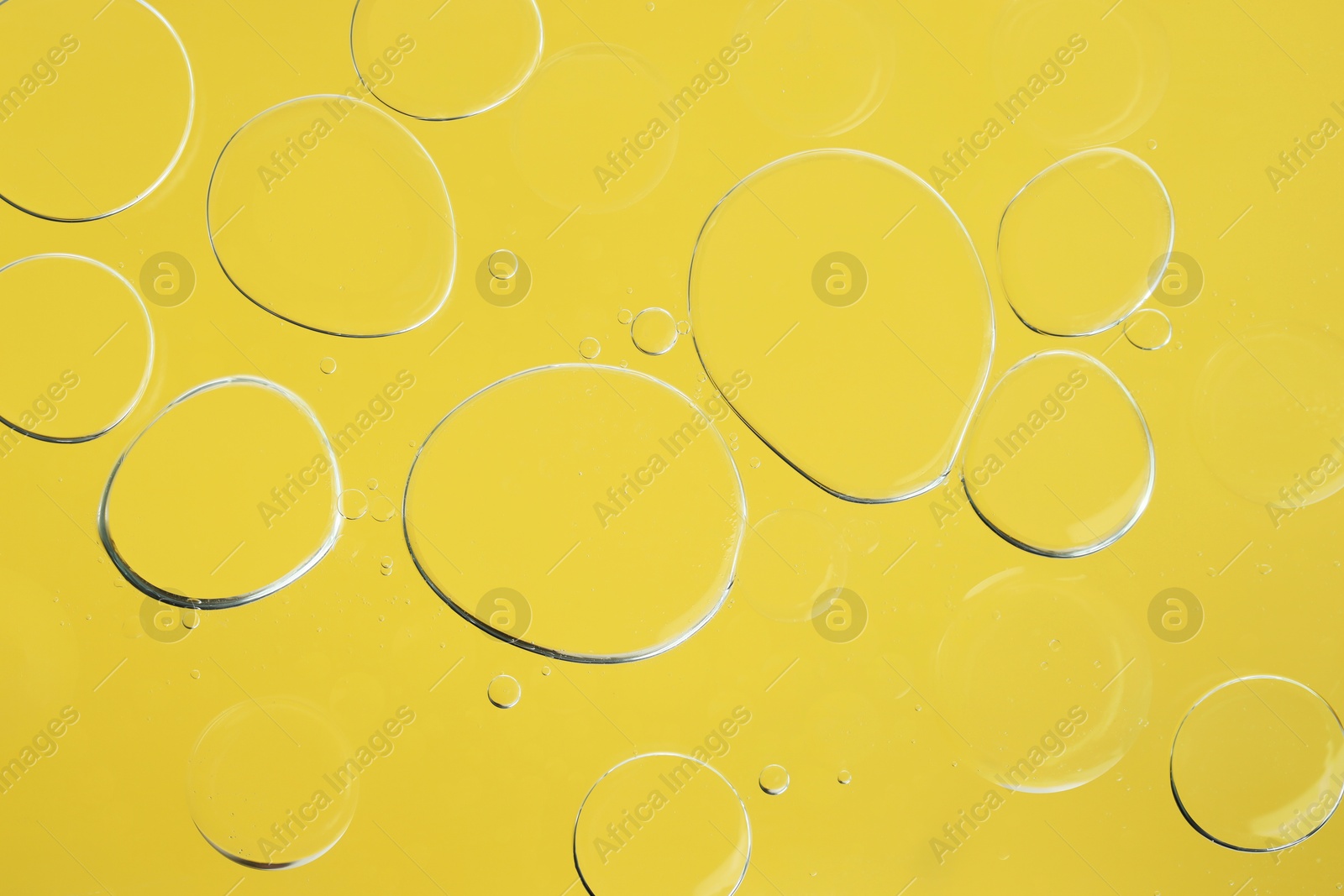 Photo of Sample of cosmetic oil on yellow background, macro view