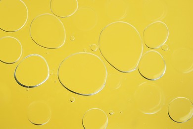 Photo of Sample of cosmetic oil on yellow background, macro view