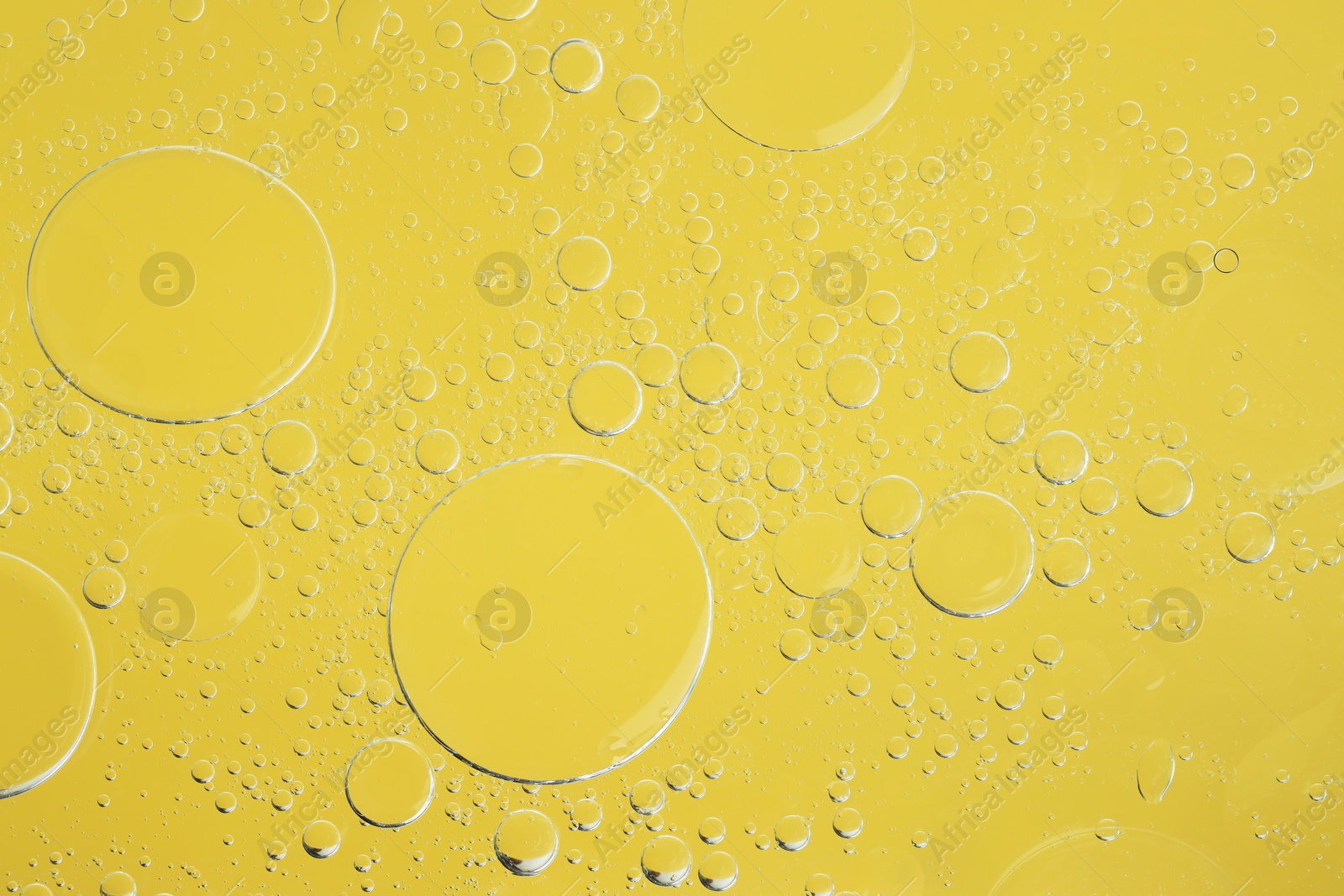 Photo of Sample of cosmetic oil on yellow background, macro view