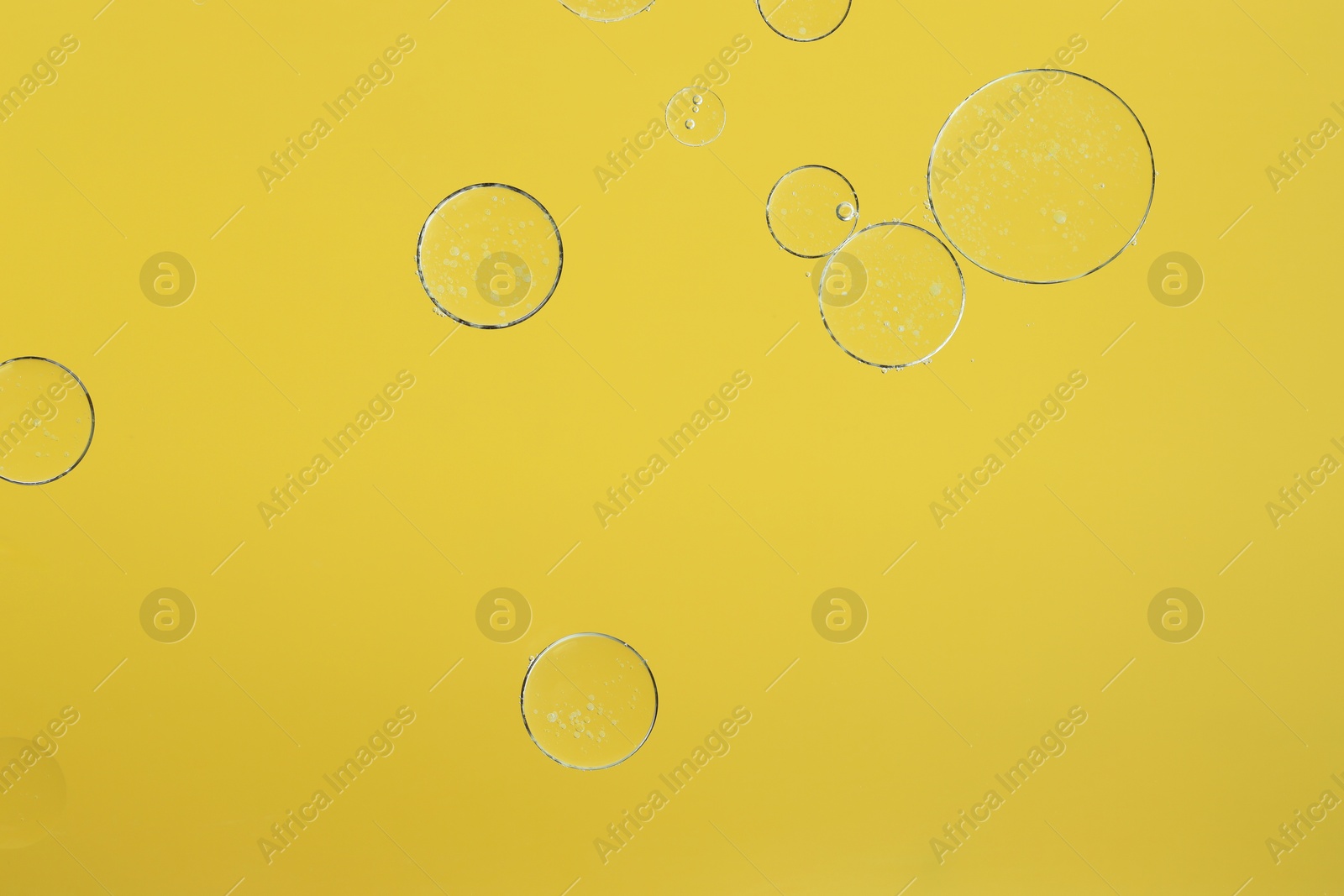 Photo of Sample of cosmetic oil on yellow background, macro view