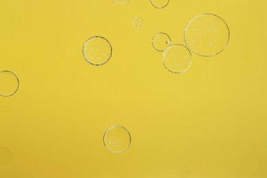 Sample of cosmetic oil on yellow background, macro view