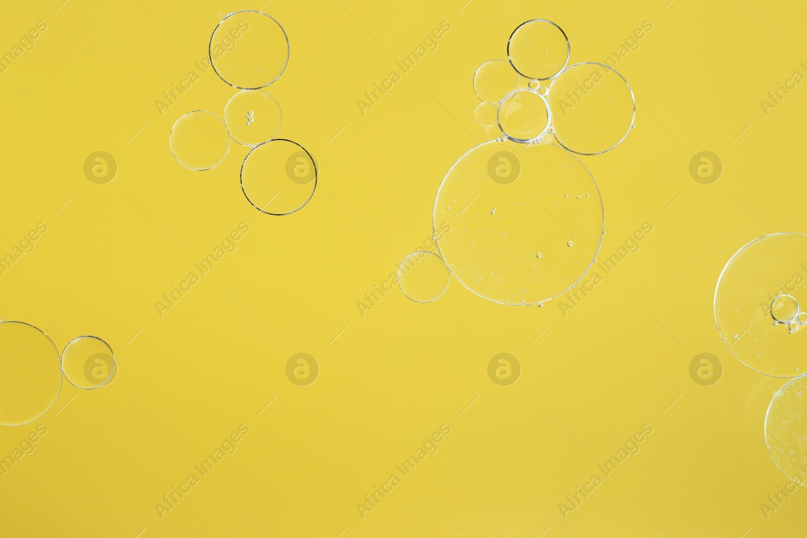 Photo of Sample of cosmetic oil on yellow background, macro view