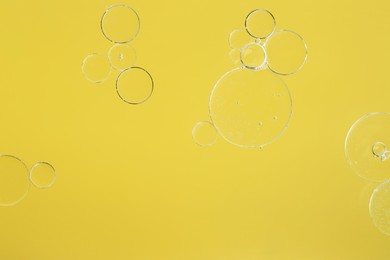 Photo of Sample of cosmetic oil on yellow background, macro view