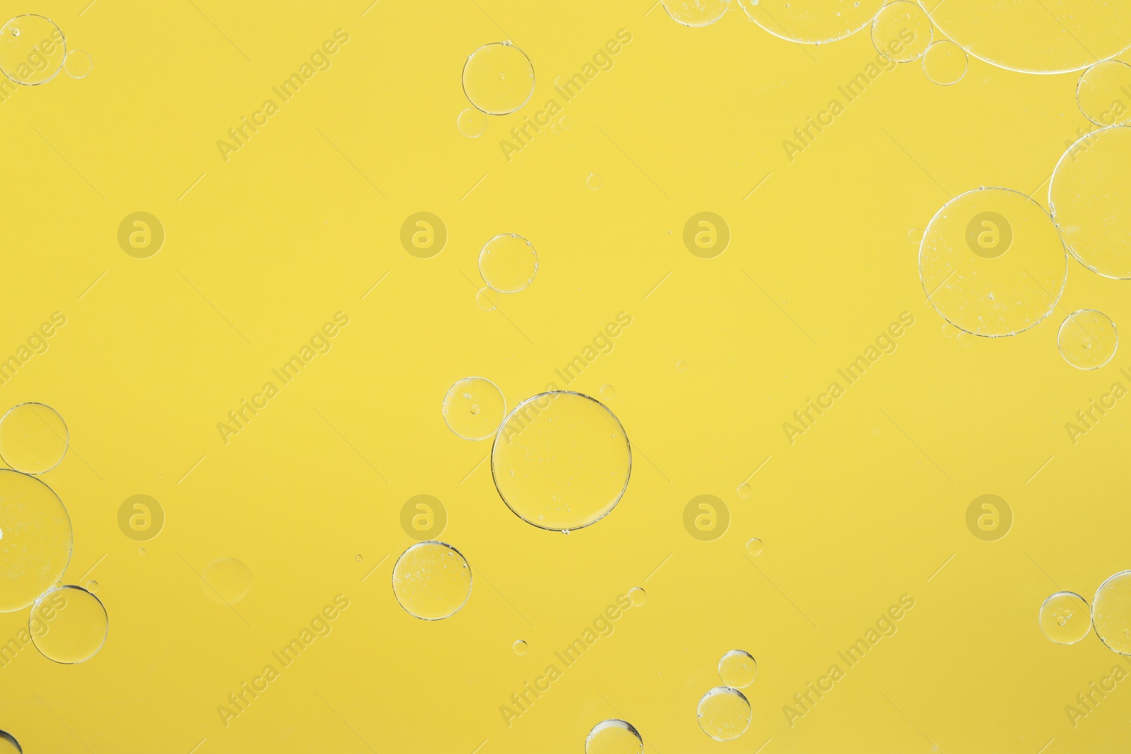 Photo of Sample of cosmetic oil on yellow background, macro view