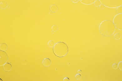 Photo of Sample of cosmetic oil on yellow background, macro view