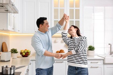 Photo of Happy lovely couple dancing together in kitchen