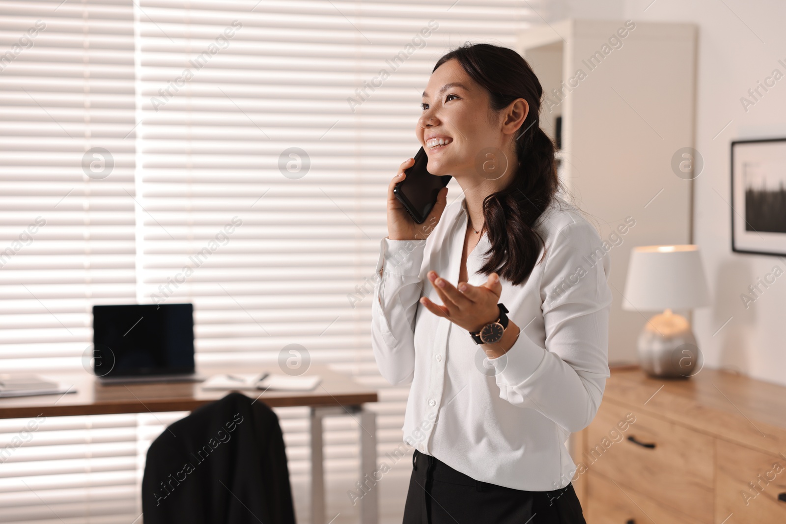 Photo of Smiling businesswoman talking on smartphone in office. Space for text