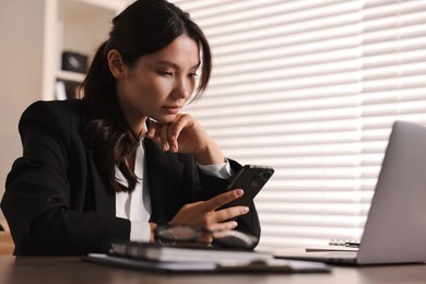 Beautiful young businesswoman using smartphone in office