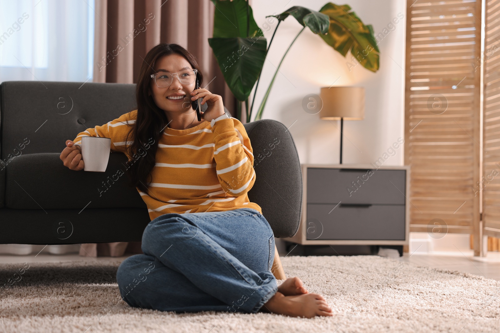 Photo of Smiling woman talking on smartphone at home