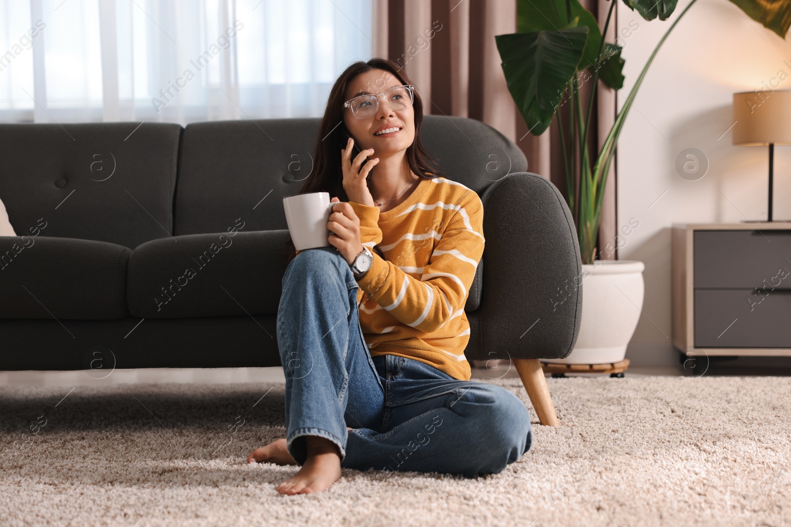 Photo of Smiling woman talking on smartphone at home