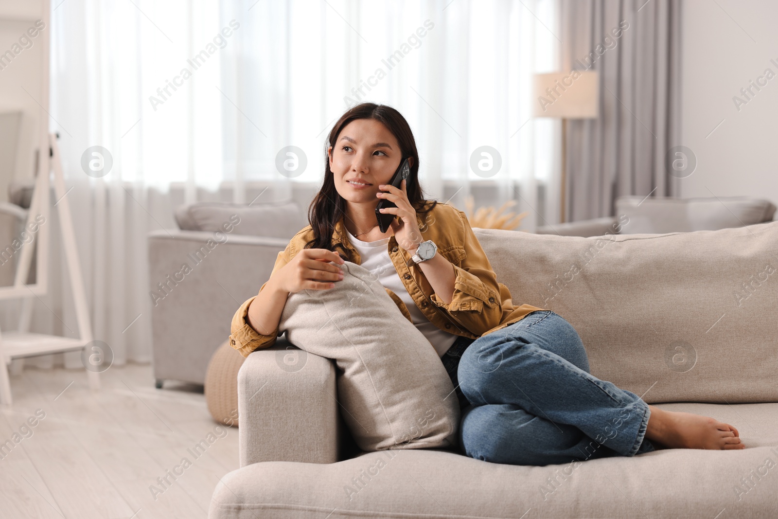 Photo of Smiling woman talking on smartphone at home