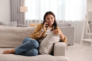 Photo of Smiling woman talking on smartphone at home