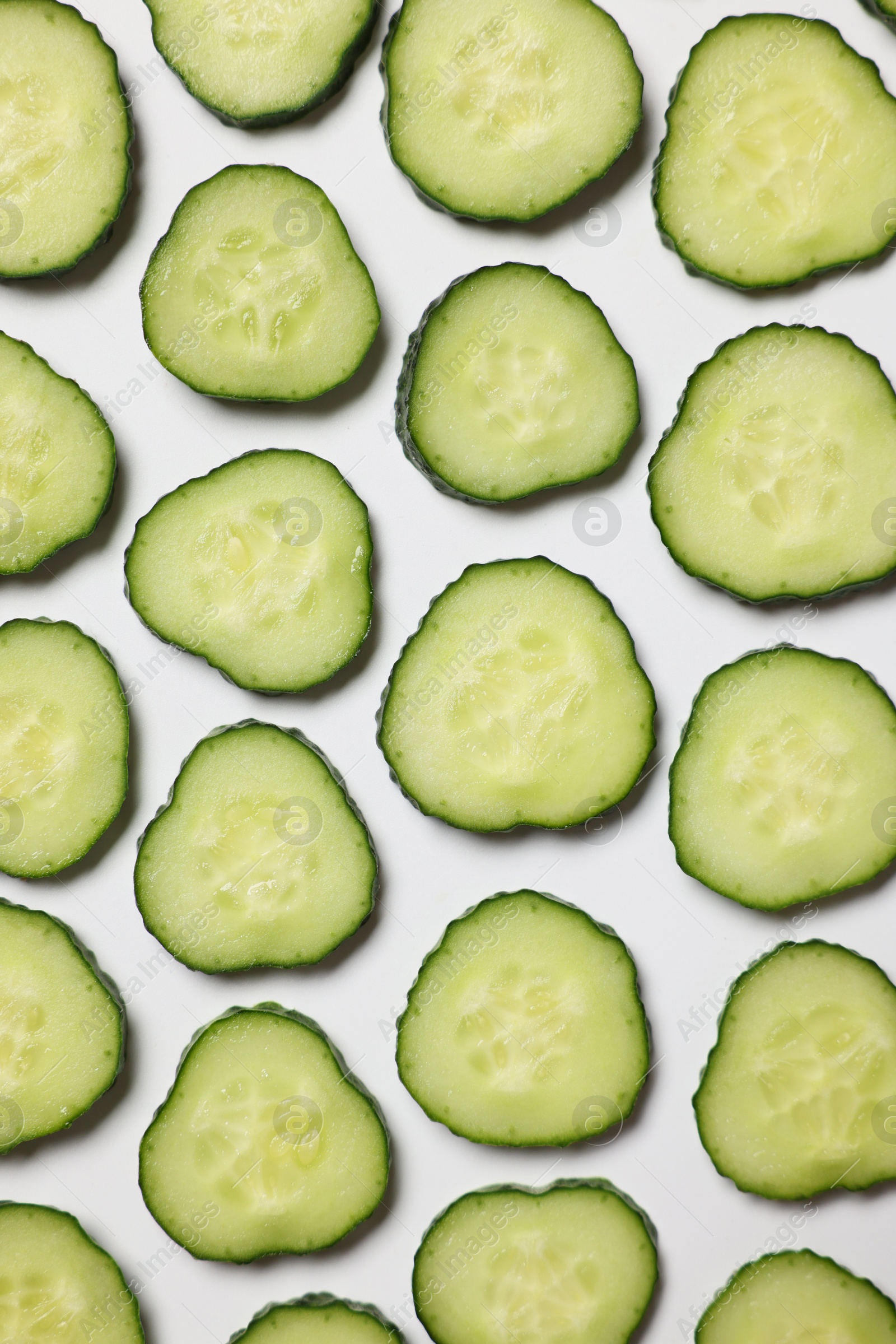 Photo of Slices of fresh cucumbers on white background, flat lay