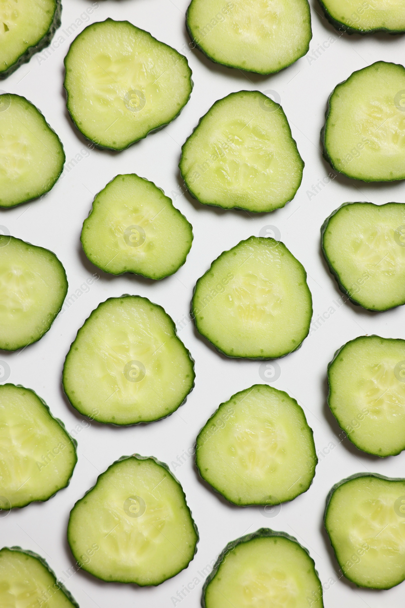 Photo of Slices of fresh cucumbers on white background, flat lay