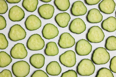 Photo of Slices of fresh cucumbers on white background, flat lay