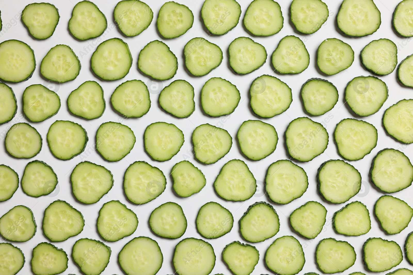 Photo of Slices of fresh cucumbers on white background, flat lay