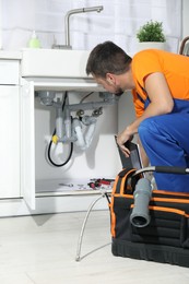 Photo of Professional plumber fixing piping system at home