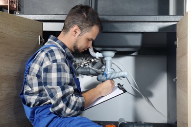 Photo of Professional plumber fixing piping system at home