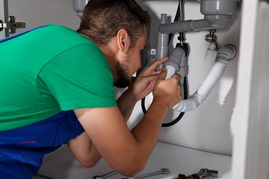 Professional plumber fixing piping system at home