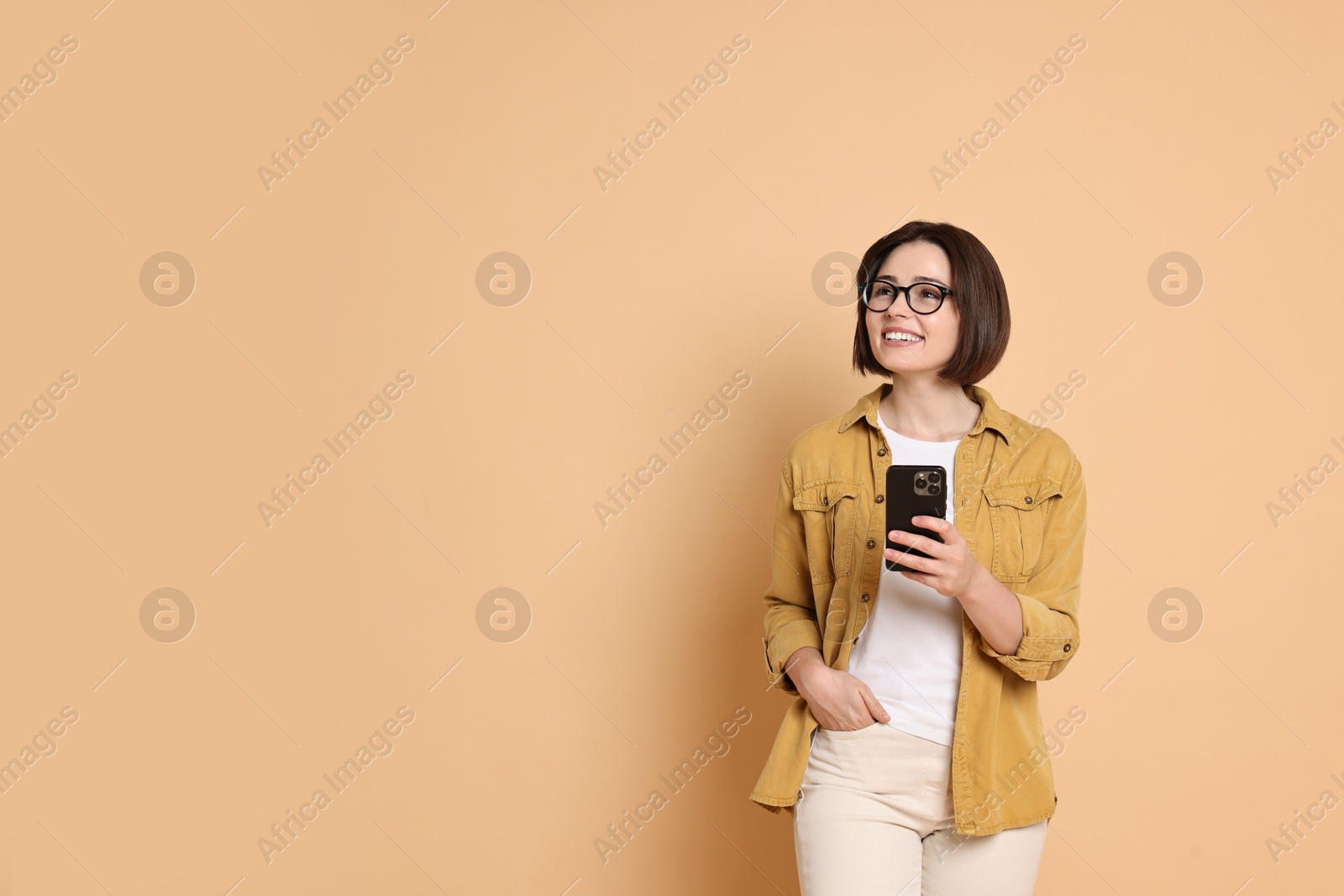 Photo of Smiling woman with smartphone on beige background. Space for text