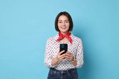 Smiling woman with smartphone on light blue background