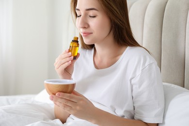 Photo of Woman with aroma diffuser and bottle of essential oil at home