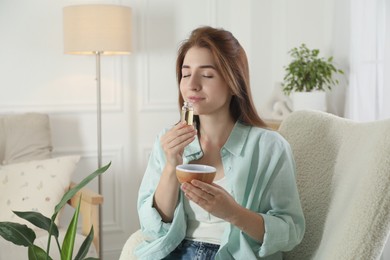 Woman with aroma diffuser and bottle of essential oil at home