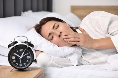 Sleepy woman waking up in bed at lunch time