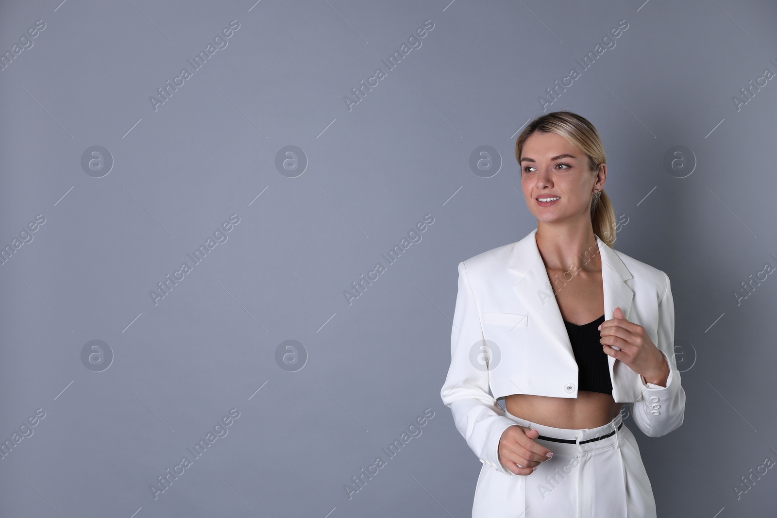 Photo of Beautiful woman in stylish white suit on grey background, space for text