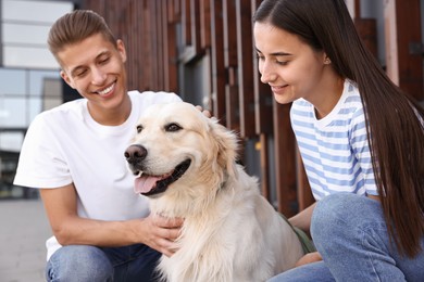 Photo of Happy couple with cute Golden Retriever dog outdoors