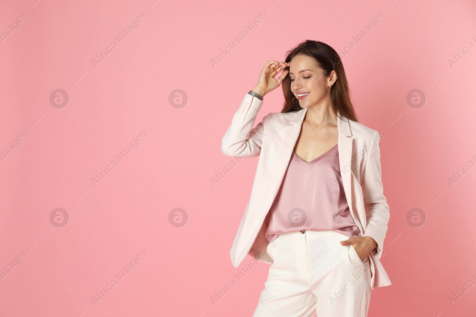 Photo of Beautiful woman in stylish white suit on pink background, space for text