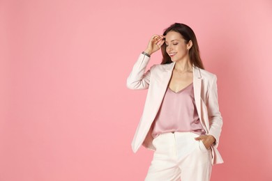 Photo of Beautiful woman in stylish white suit on pink background, space for text