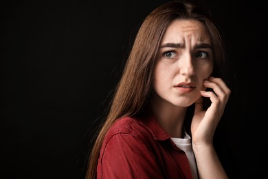 Photo of Portrait of scared woman on black background. Space for text