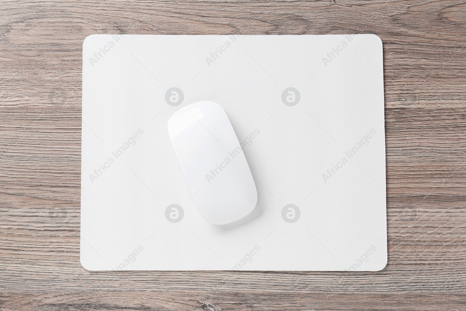 Photo of Computer mouse with mousepad on wooden desk, top view