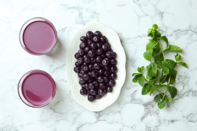 Tasty fresh acai juice in glasses, mint and berries on white marble table, flat lay