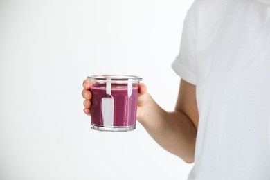 Photo of Woman with glass of tasty fresh acai juice on light grey background, closeup