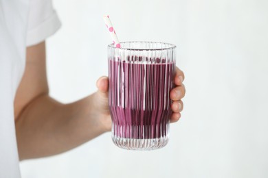 Photo of Woman with glass of tasty fresh acai juice on light grey background, closeup