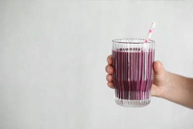 Photo of Woman with glass of tasty fresh acai juice on light grey background, closeup. Space for text