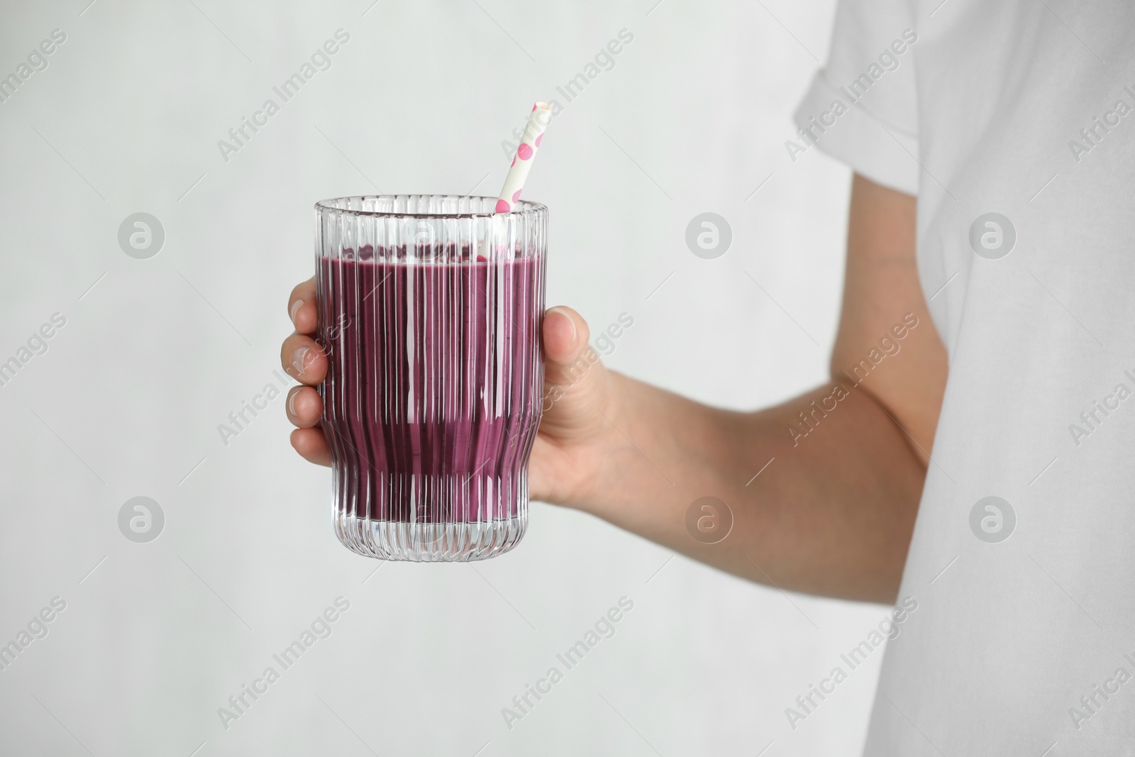 Photo of Woman with glass of tasty fresh acai juice on light grey background, closeup