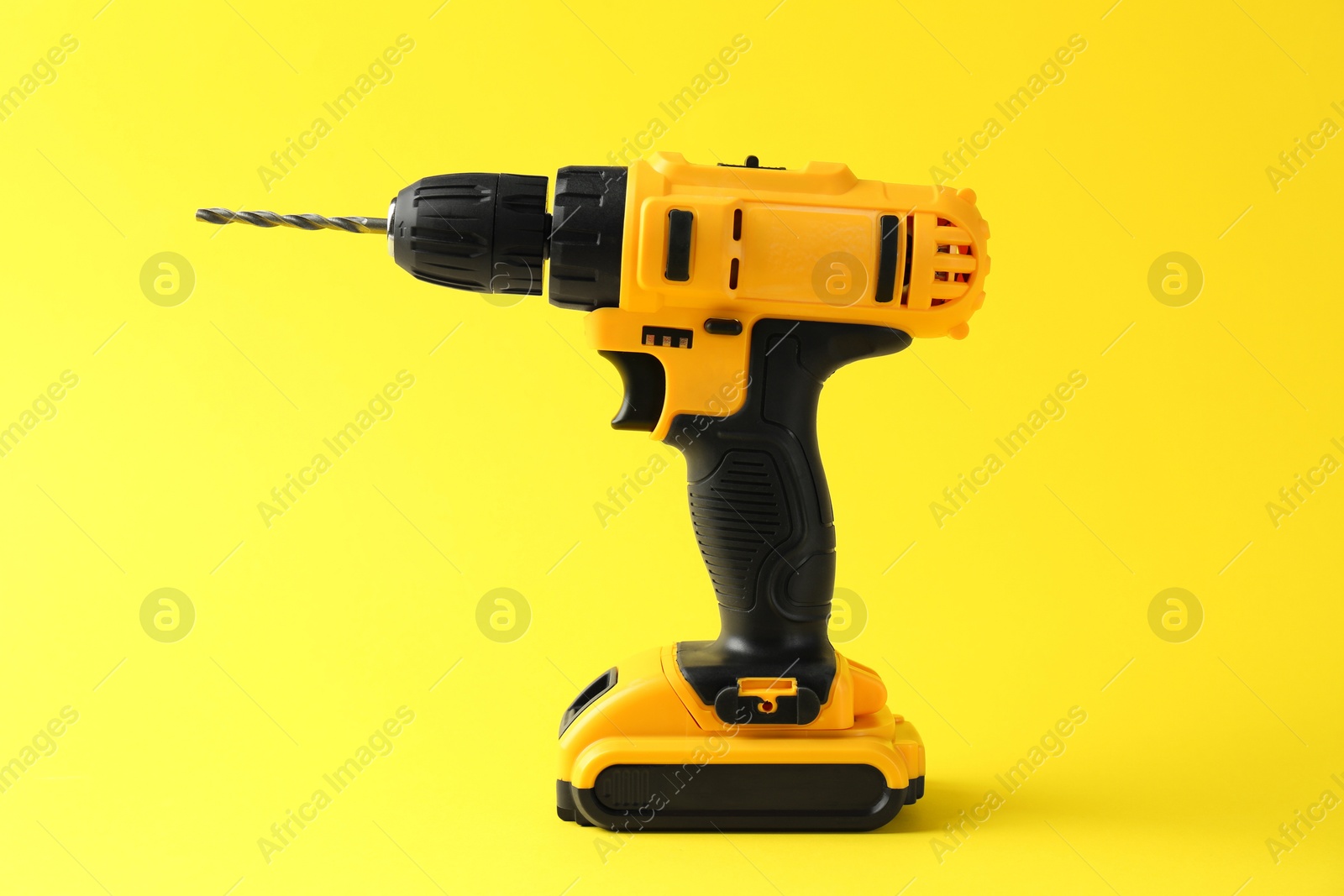 Photo of Modern cordless electric drill on yellow background