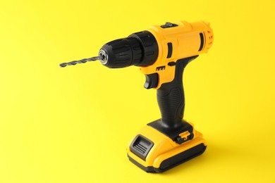 Photo of Modern cordless electric drill on yellow background