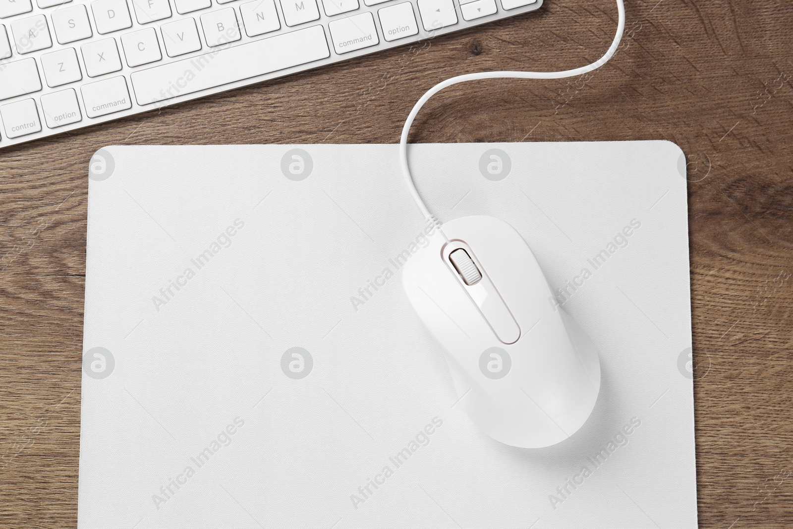 Photo of Computer mouse with mousepad and keyboard on wooden table, flat lay