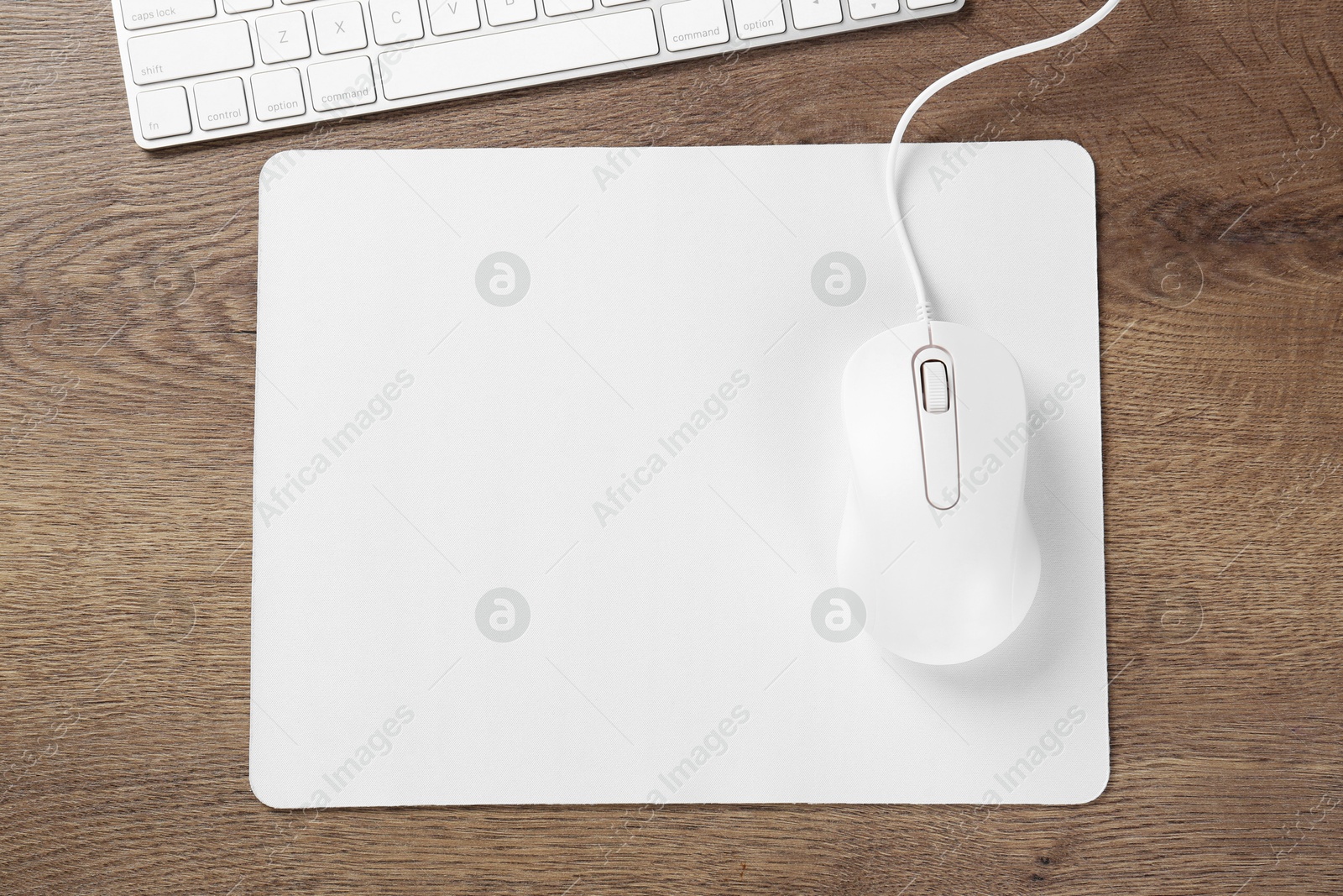 Photo of Computer mouse with mousepad and keyboard on wooden table, flat lay